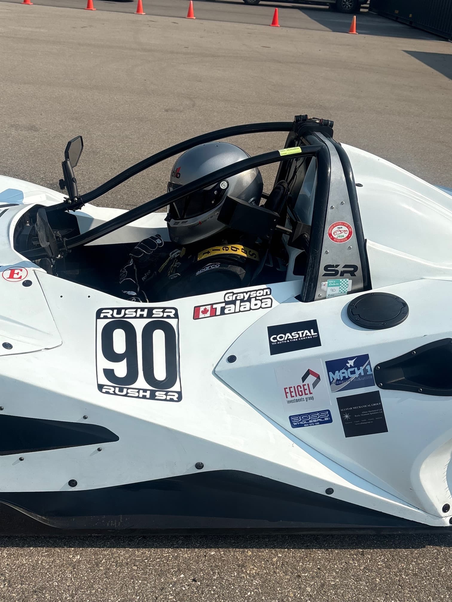 Grayson Talaba seated in his white number 90 Rush SR race car